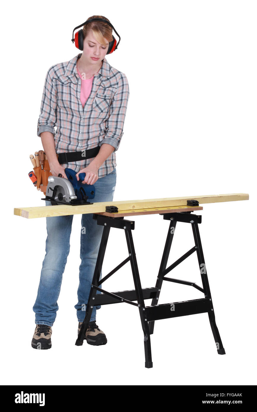 Femme à l'aide d'une scie circulaire pour couper une planche en bois Banque D'Images