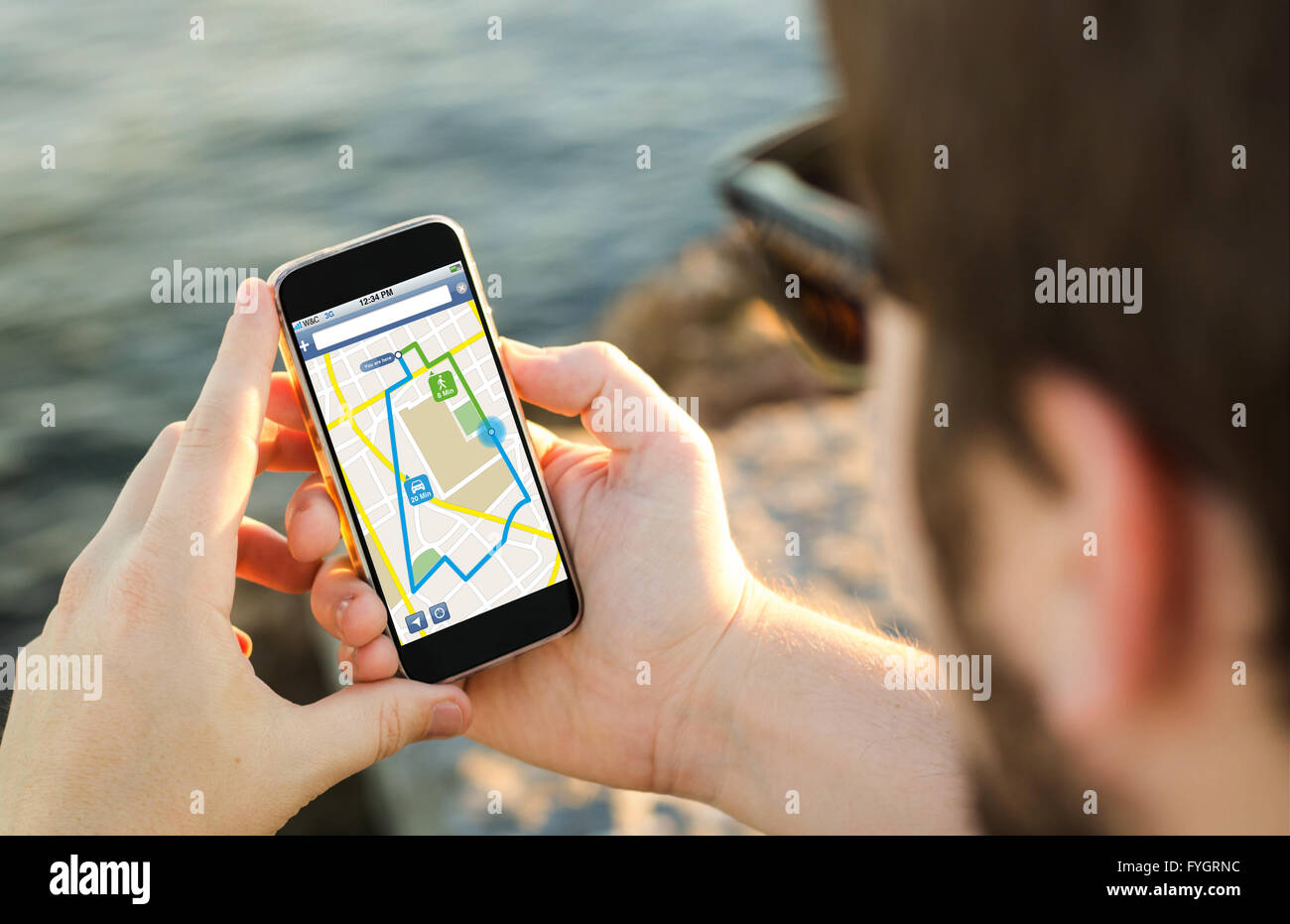L'homme sur la côte en utilisant son smartphone pour planifier un itinéraire. Tous les graphiques de l'écran sont constitués. Banque D'Images
