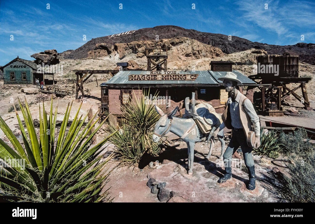 Le temps s'arrête pour un prospecteur et son âne, en face de la mine de Maggie dans une "ville fantôme" appelé calicot, un camp minier qui a produit plus de 20 millions de dollars de l'argent à la fin des années 1800 dans le sud de la Californie, USA. Cette rude communauté difficiles une fois vanté 3 500 résidents et 22 saloons, mais il était désert après le minerai d'argent s'est épuisé. Seulement cinq bâtiments d'origine existait encore lorsque la restauration historique de cette ancienne ville de l'Ouest a commencé en 1951. Aujourd'Calico Ghost Town est un comté de Park qui est devenu une attraction touristique majeure. Banque D'Images