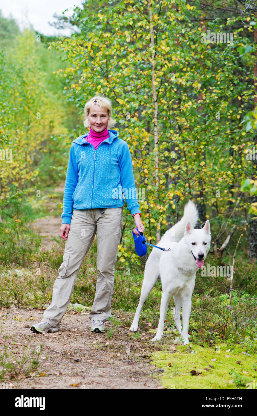La femme avec un chien marche dans un bois de l'automne Banque D'Images