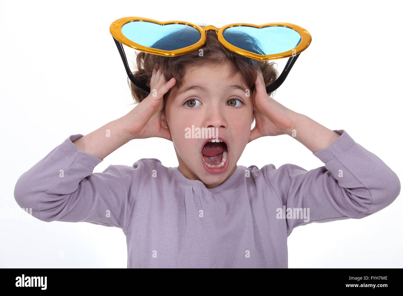 Petite fille hurlant avec d'énormes lunettes drôles sur la tête Photo Stock  - Alamy