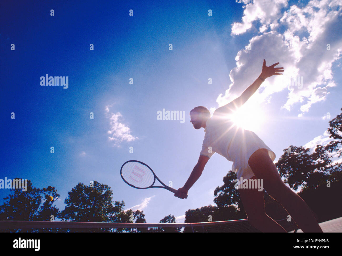 Vue en contre-jour de joueur de tennis masculin frapper la balle avec une raquette Banque D'Images