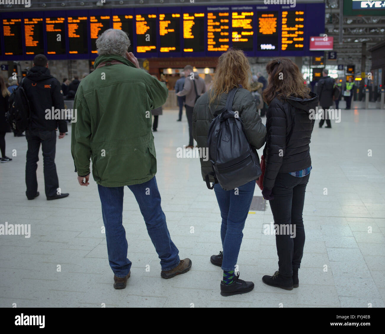 Famille dans la gare centrale de Glasgow téléphonant à bord des arrivées Banque D'Images