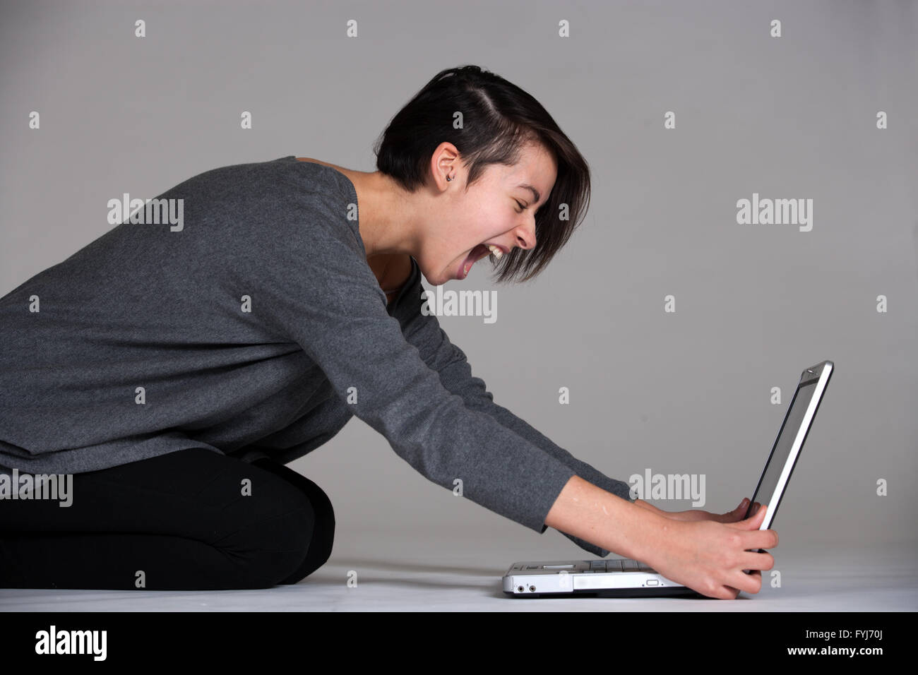 Jeune femme sur le plancher avec un ordinateur portable Banque D'Images