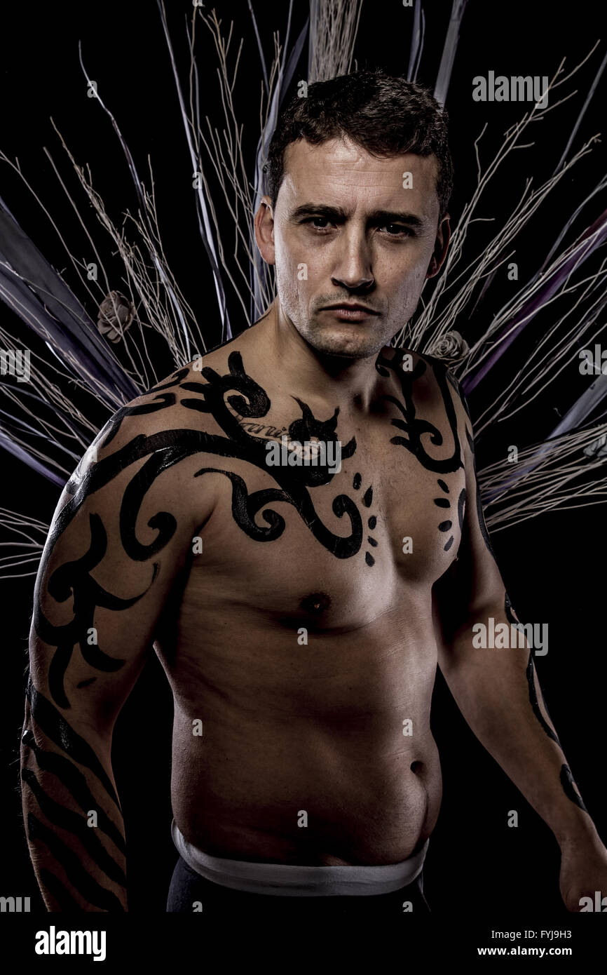 Artistique. Jeune modèle rétro attrayants dans des vêtements à l'ancienne tribu sauvage. Tattoo. L'homme sauvage indigène Banque D'Images