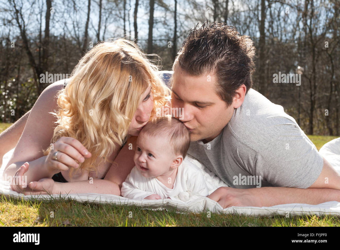 Les jeunes parents s'embrassent le bébé Banque D'Images