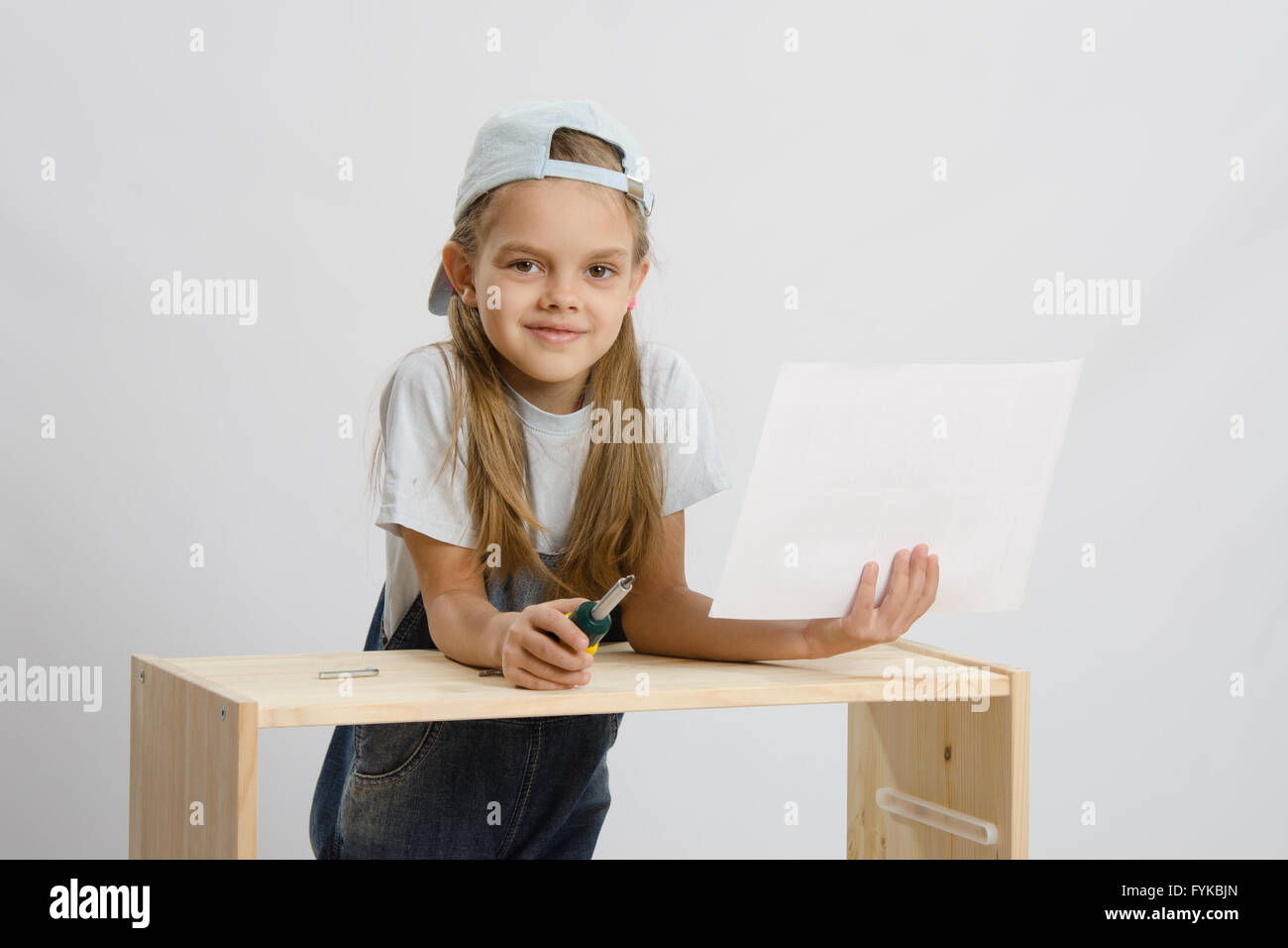 Girl-collectionneur de meubles avec un tournevis et le dessin de mobilier recueille Banque D'Images