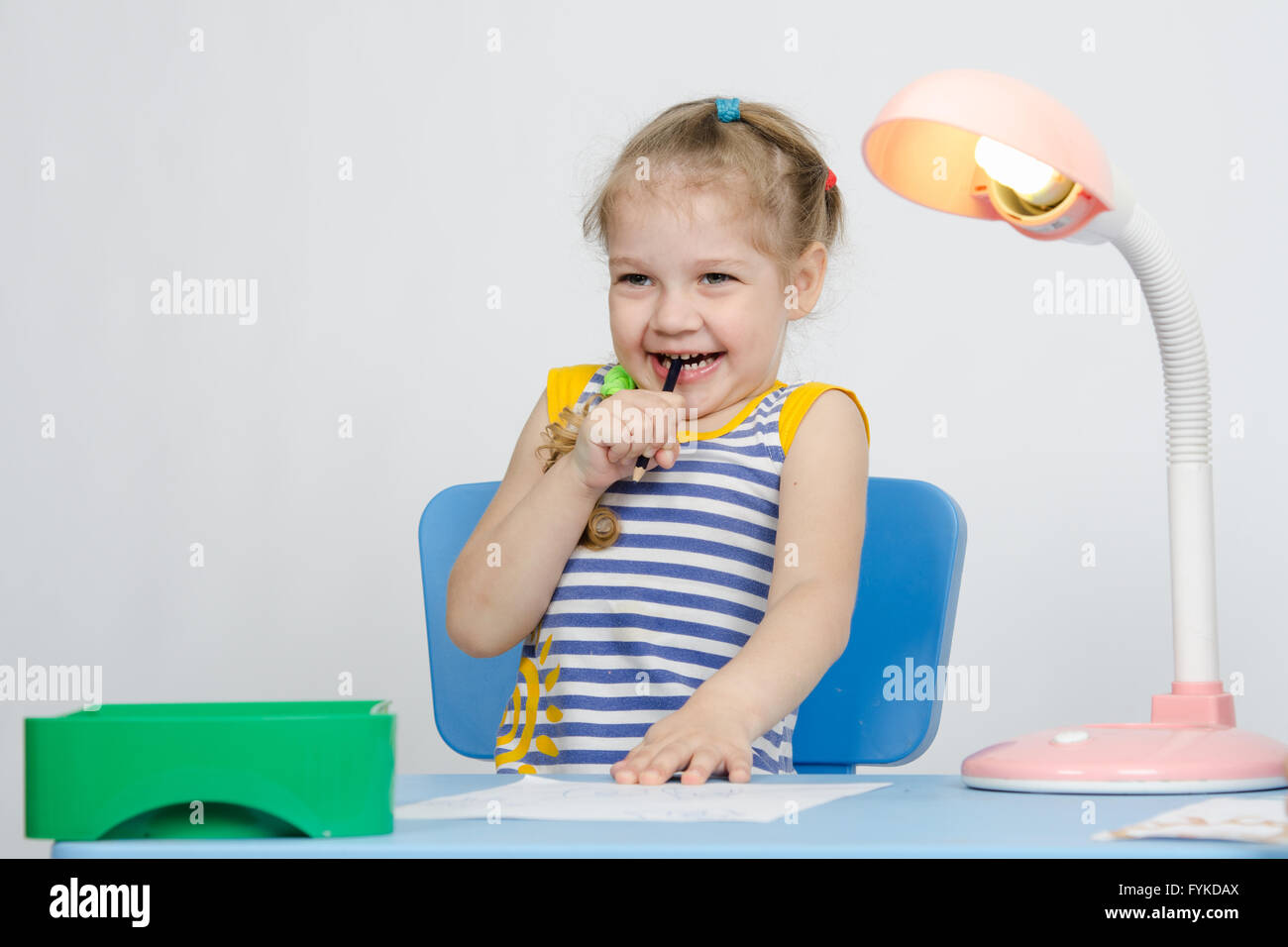 Girl laughing coincé un crayon dans sa bouche Banque D'Images