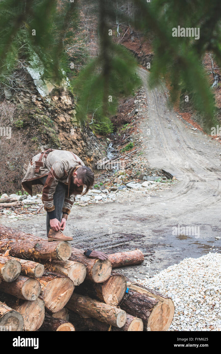 Les jeunes hommes sur des rondins dans la forêt. Cuir et jeans. La mode en plein air Banque D'Images