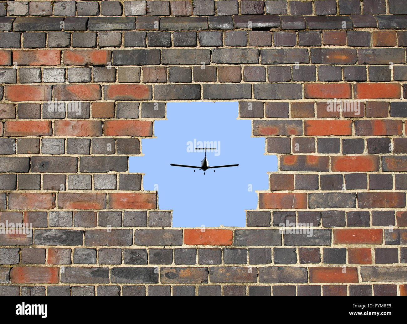 Petit avion à travers un trou dans un mur de briques Banque D'Images