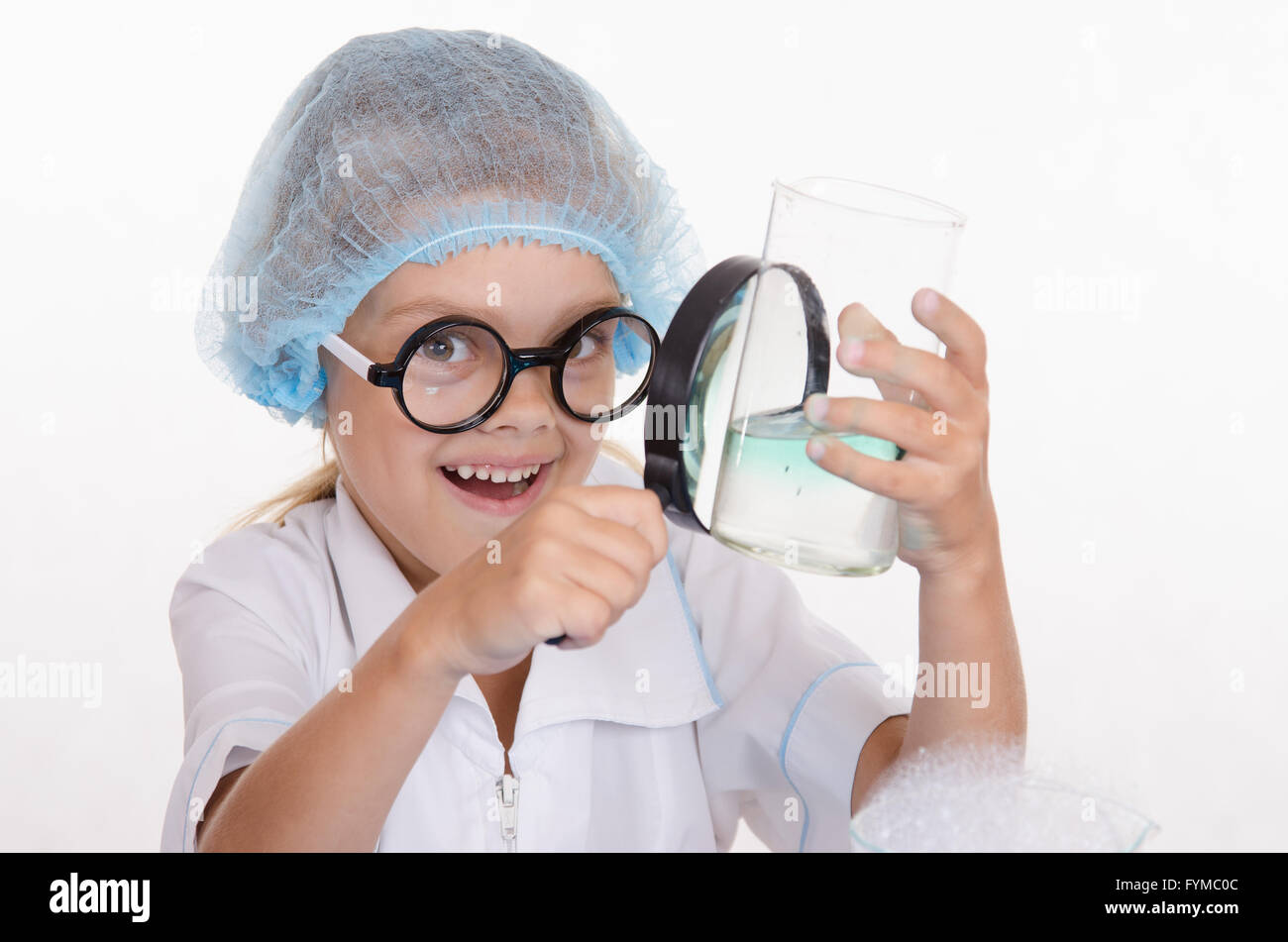 Chimiste fille examine flasque sous une loupe Banque D'Images