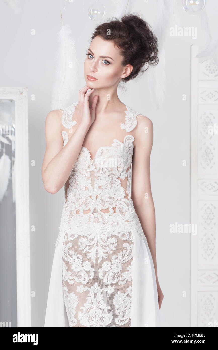 Jeune mariée élégante dans une robe en dentelle. Elle regarde droit dans le visualiseur. Elle a les cheveux noirs bouclés et une belle peau bronzée. Whi Banque D'Images