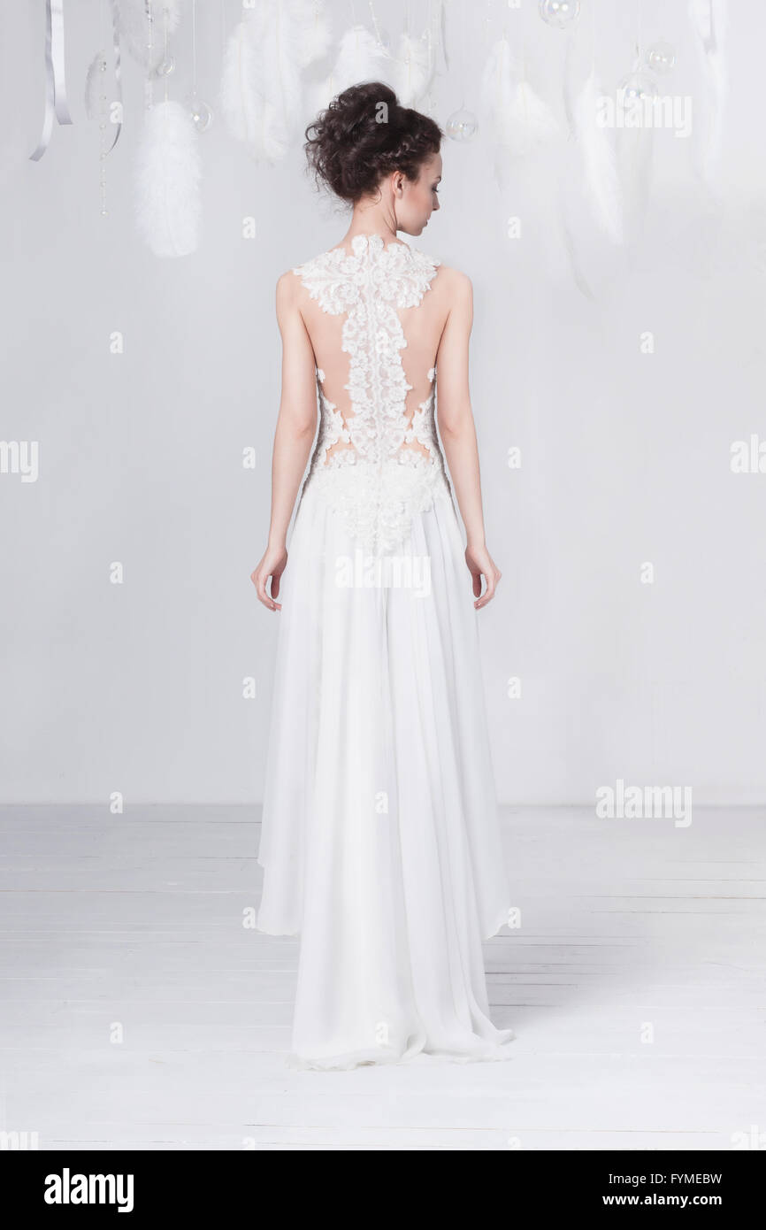Grande et mince jeune mariée dans une luxueuse dentelle robe de mariage. Elle se tient debout avec son dos à l'observateur. Elle a les cheveux foncés. Fe blanc Banque D'Images