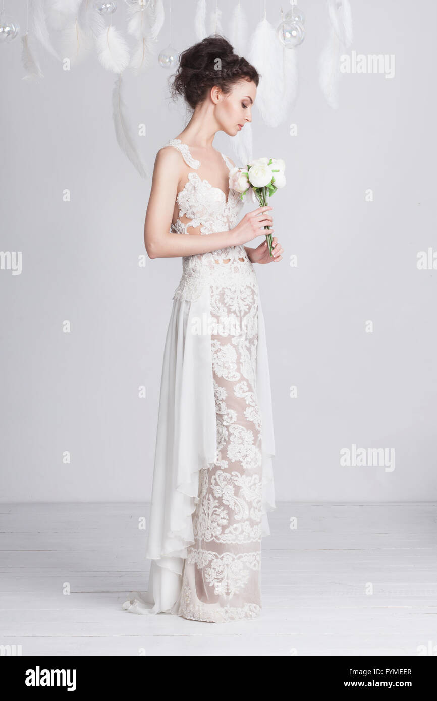 Grande et mince jeune mariée dans une luxueuse dentelle robe de mariage. Elle a une belle peau bronzée. La robe est translucide. Fe blanc Banque D'Images