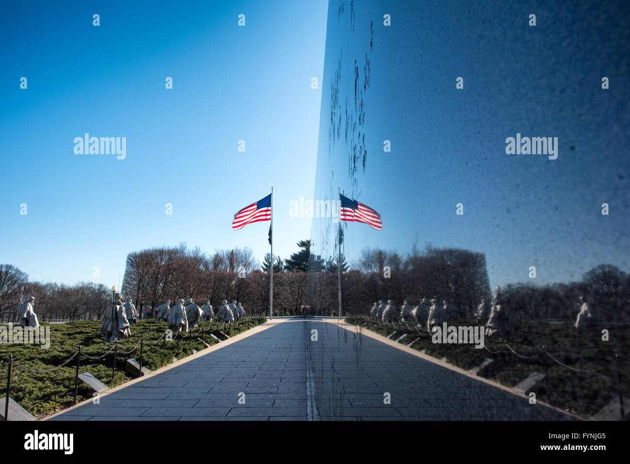 Mur mural du mémorial des anciens combattants de la guerre de Corée Washington DC // WASHINGTON DC — le mur mural en granit noir reflète les 19 statues en acier inoxydable du mémorial des anciens combattants de la guerre de Corée sur le National Mall. Le mur, gravé avec plus de 2 500 photographies de la guerre de Corée, s'étend sur 164 pieds le long du site commémoratif. La surface réfléchissante crée une image miroir des statues de patrouille, représentant symboliquement 38 soldats. Banque D'Images