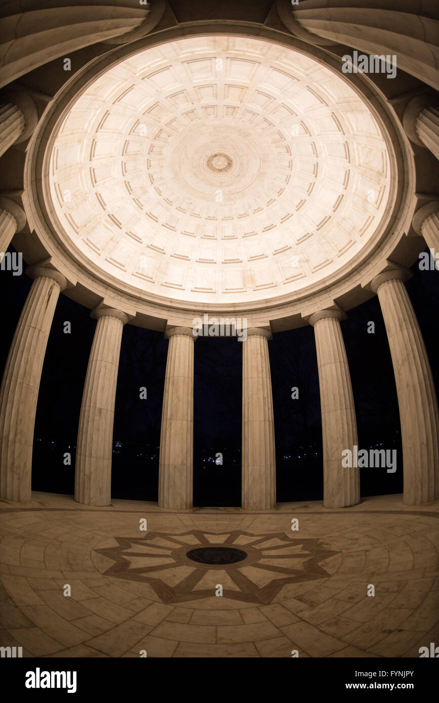 District of Columbia War Memorial Dome Interior Washington DC // WASHINGTON DC — vue intérieure du plafond et des colonnes du District of Columbia War Memorial la nuit sur le National Mall. Le mémorial circulaire, achevé en 1931, présente une construction en marbre du Vermont avec douze colonnes doriques soutenant le dôme illuminé. Cette perspective grand angle met en valeur les détails architecturaux classiques de la structure intérieure du mémorial. Banque D'Images