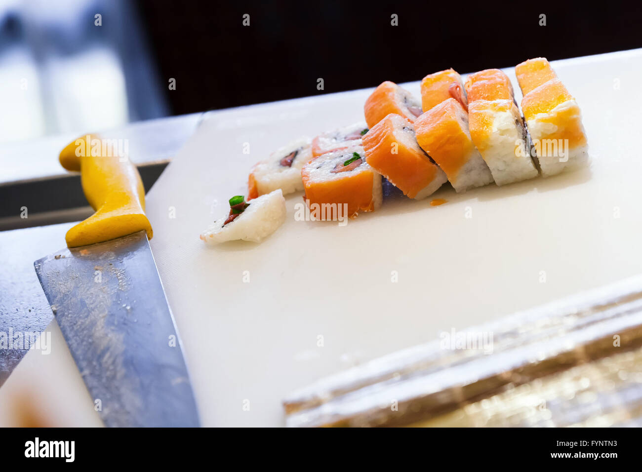 Rouleaux de sushi japonais traditionnel avec les saumons pondent sur blanc planche à découper, couteau chef. Selective focus Banque D'Images