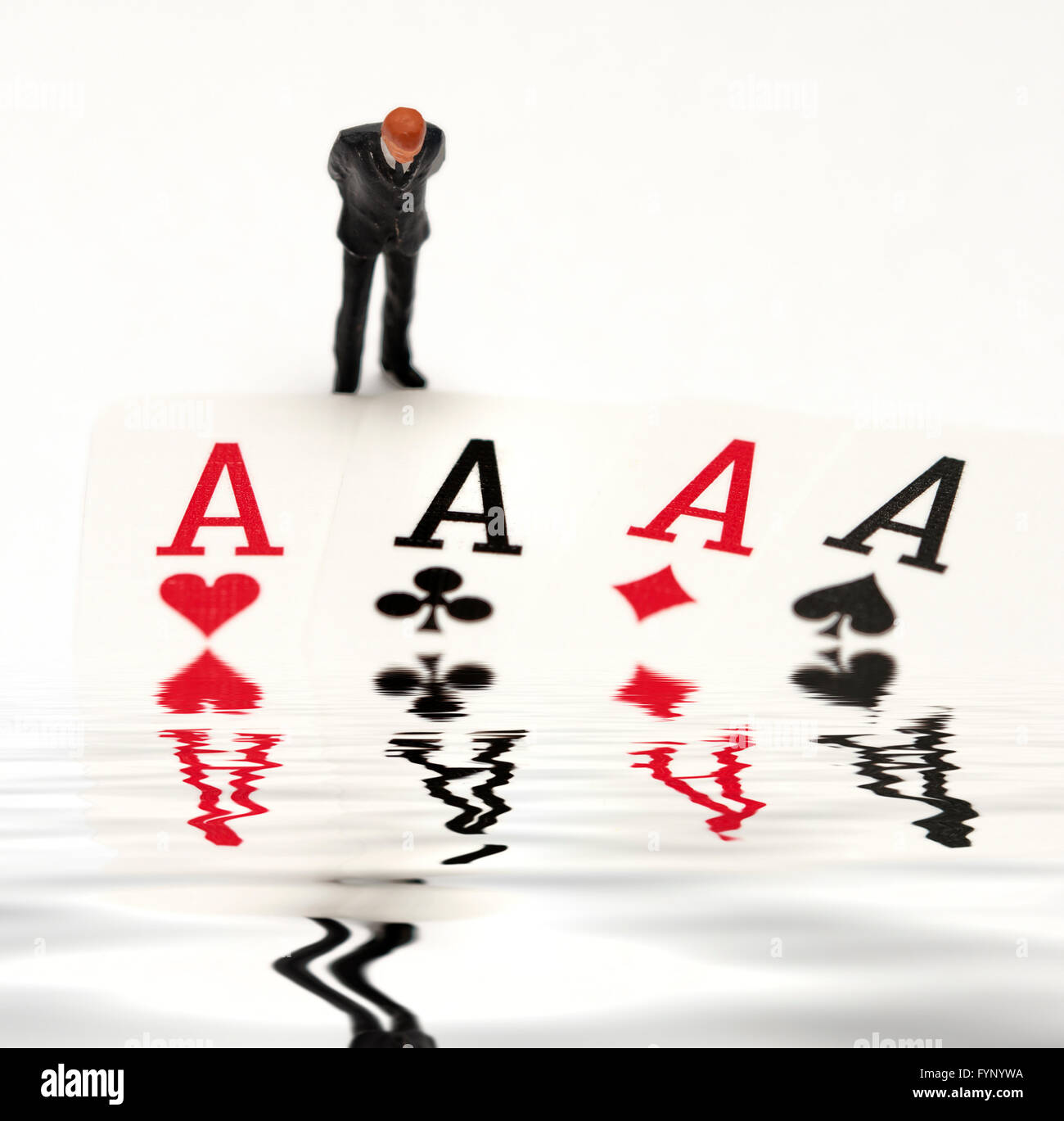 Un homme d'affaires figurine miniature en regardant 4 as d'un jeu de cartes à jouer avec un compte numérique piscine d'eau. Banque D'Images