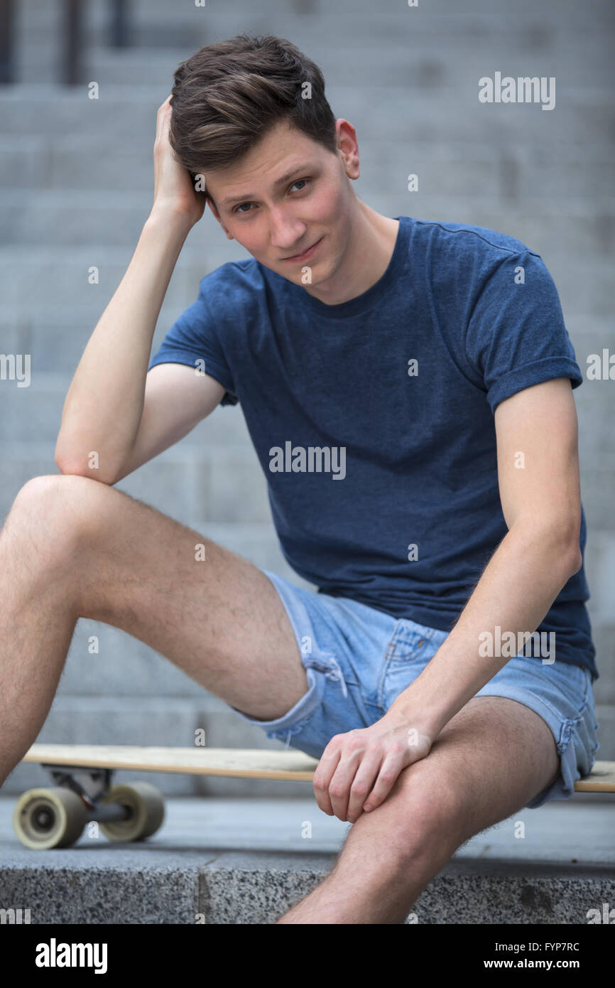 Jeune homme assis sur un longboard. Banque D'Images