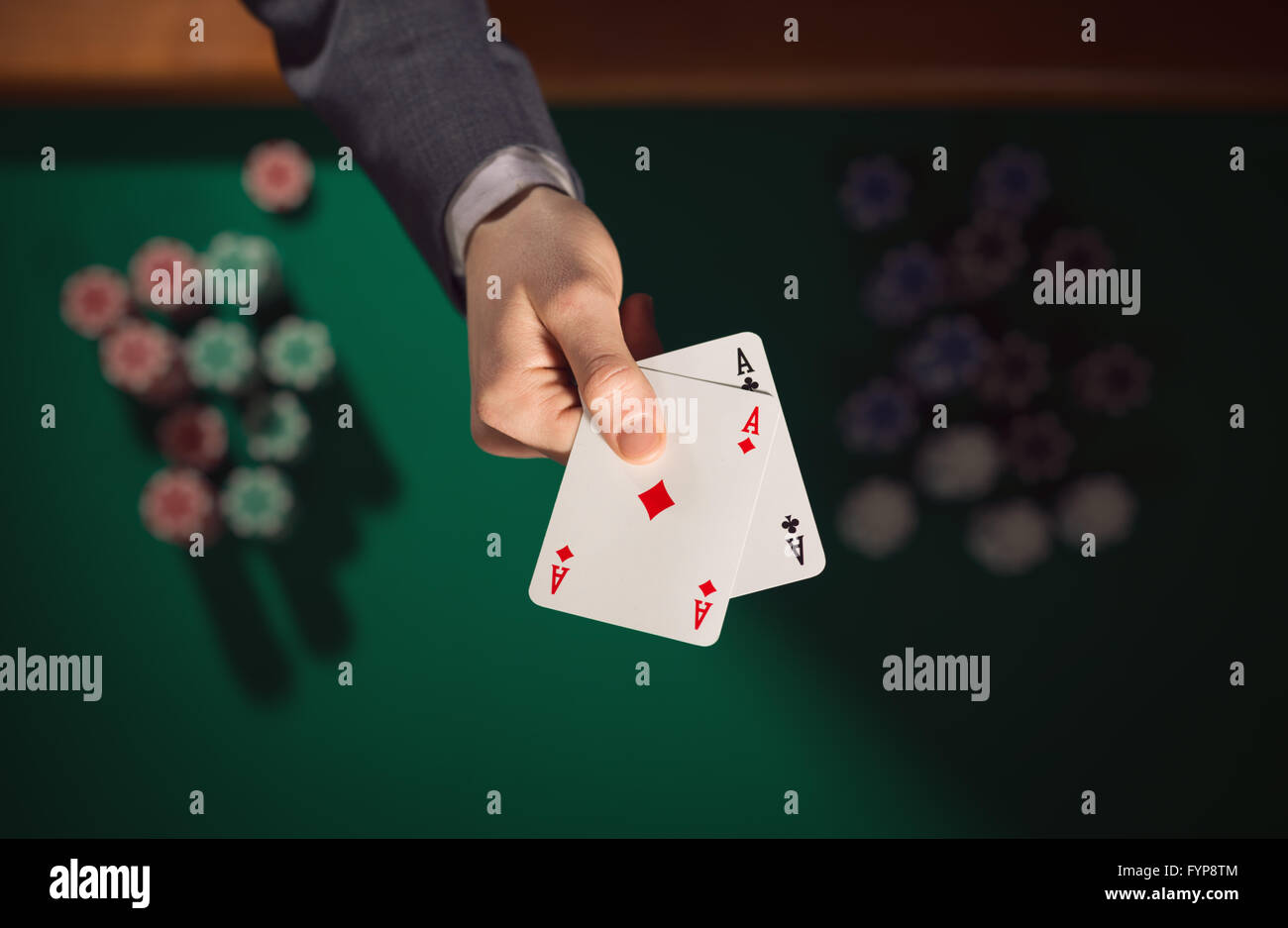 Joueur de poker homme élégant tenant deux As avec des piles de jetons sur la table verte et l'arrière-plan, Vue de dessus Banque D'Images