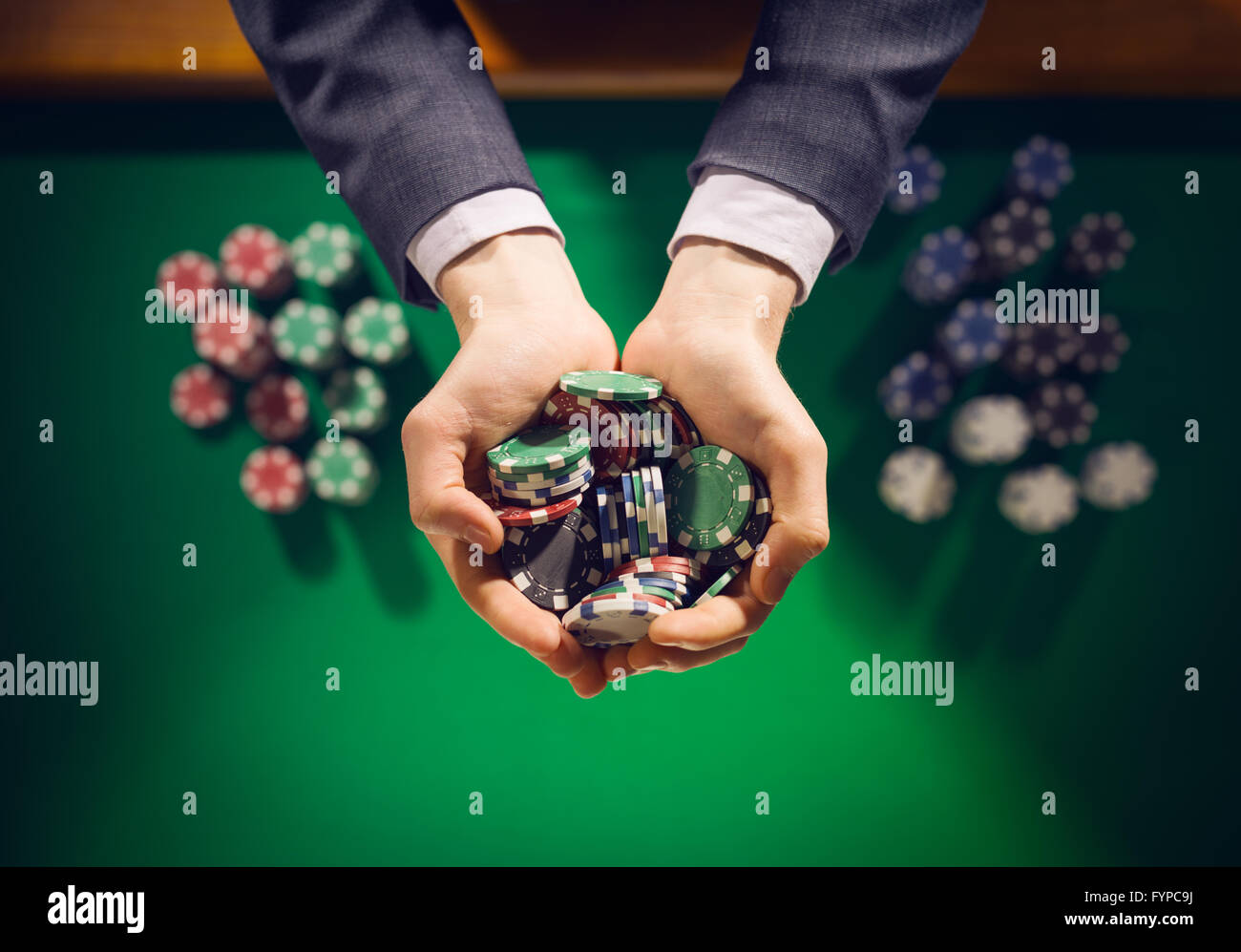 Homme élégant casino joueur tenant une poignée de jetons en arrière-plan sur la table verte, mains close up Vue de dessus Banque D'Images