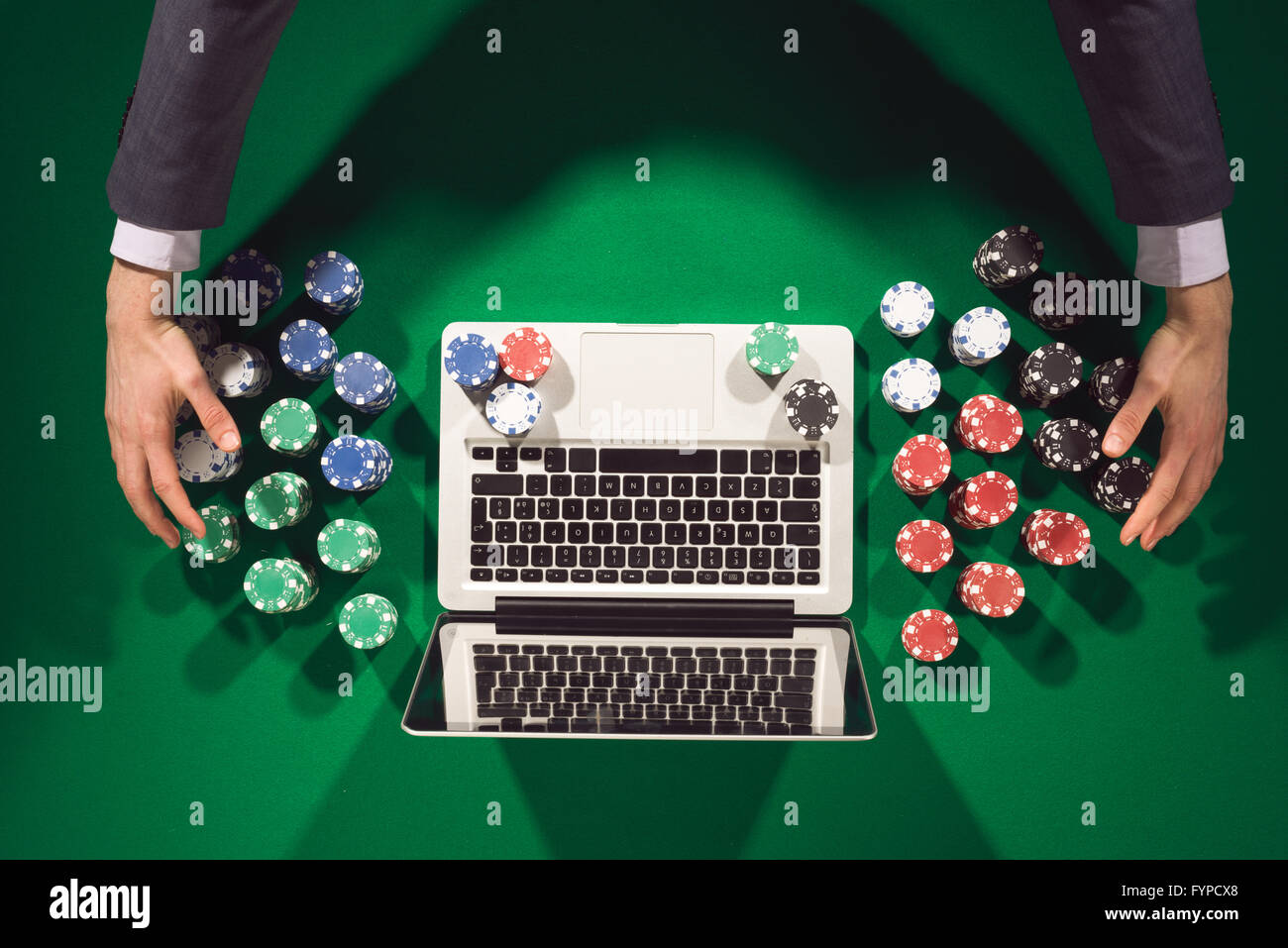 Mains du joueur en ligne avec un ordinateur portable sur la table verte Vue de dessus, il est large et de prendre tous les jetons Banque D'Images