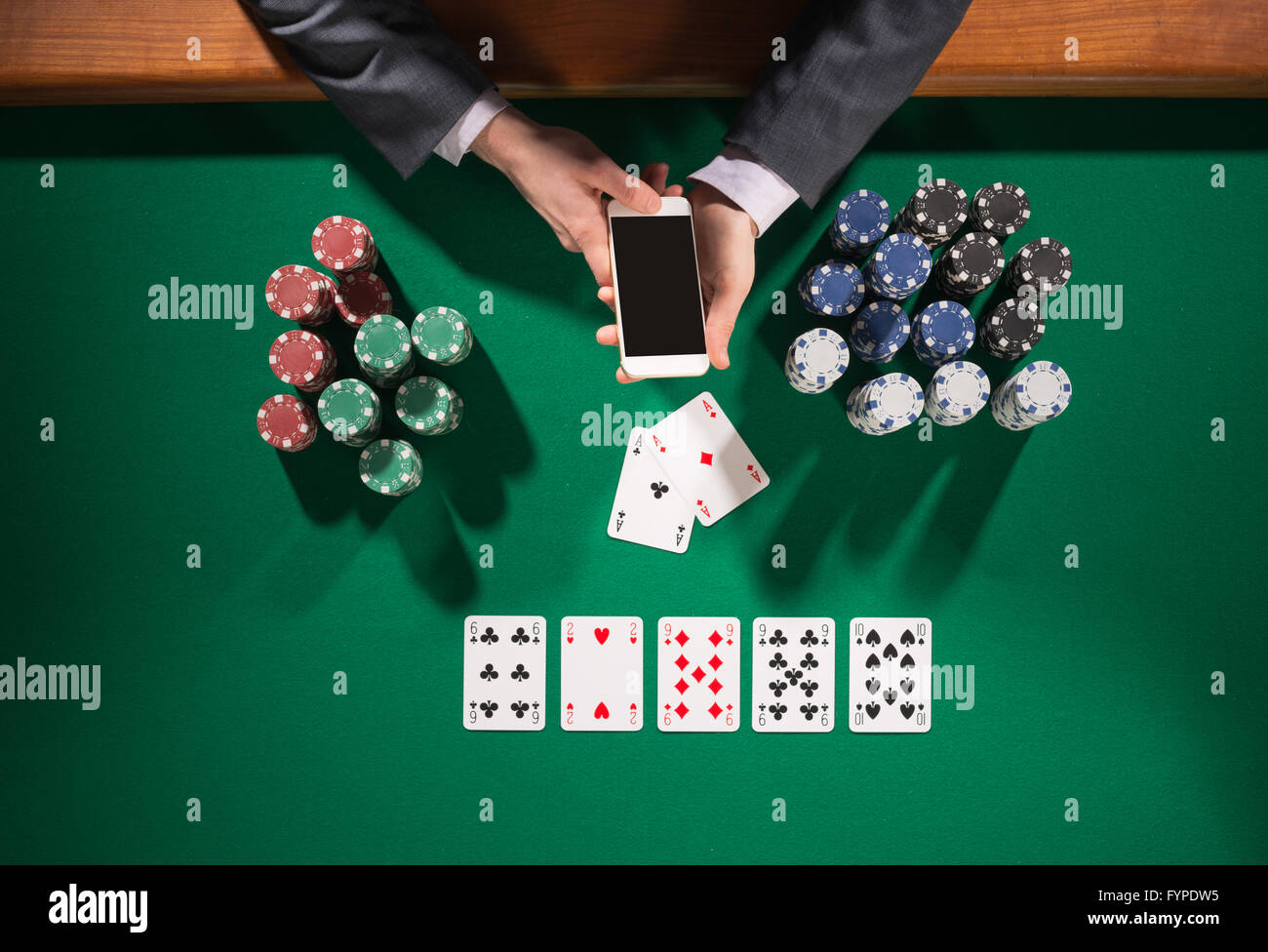 Homme élégant smartphone à l'aide d'un joueur de poker, cartes et puces stacks tout autour, green table top view Banque D'Images