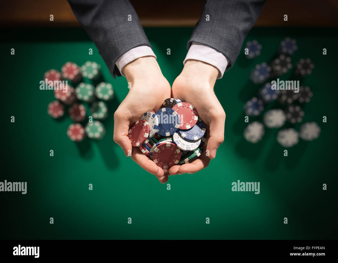Homme élégant casino joueur tenant une poignée de jetons en arrière-plan sur la table verte, mains close up Vue de dessus Banque D'Images