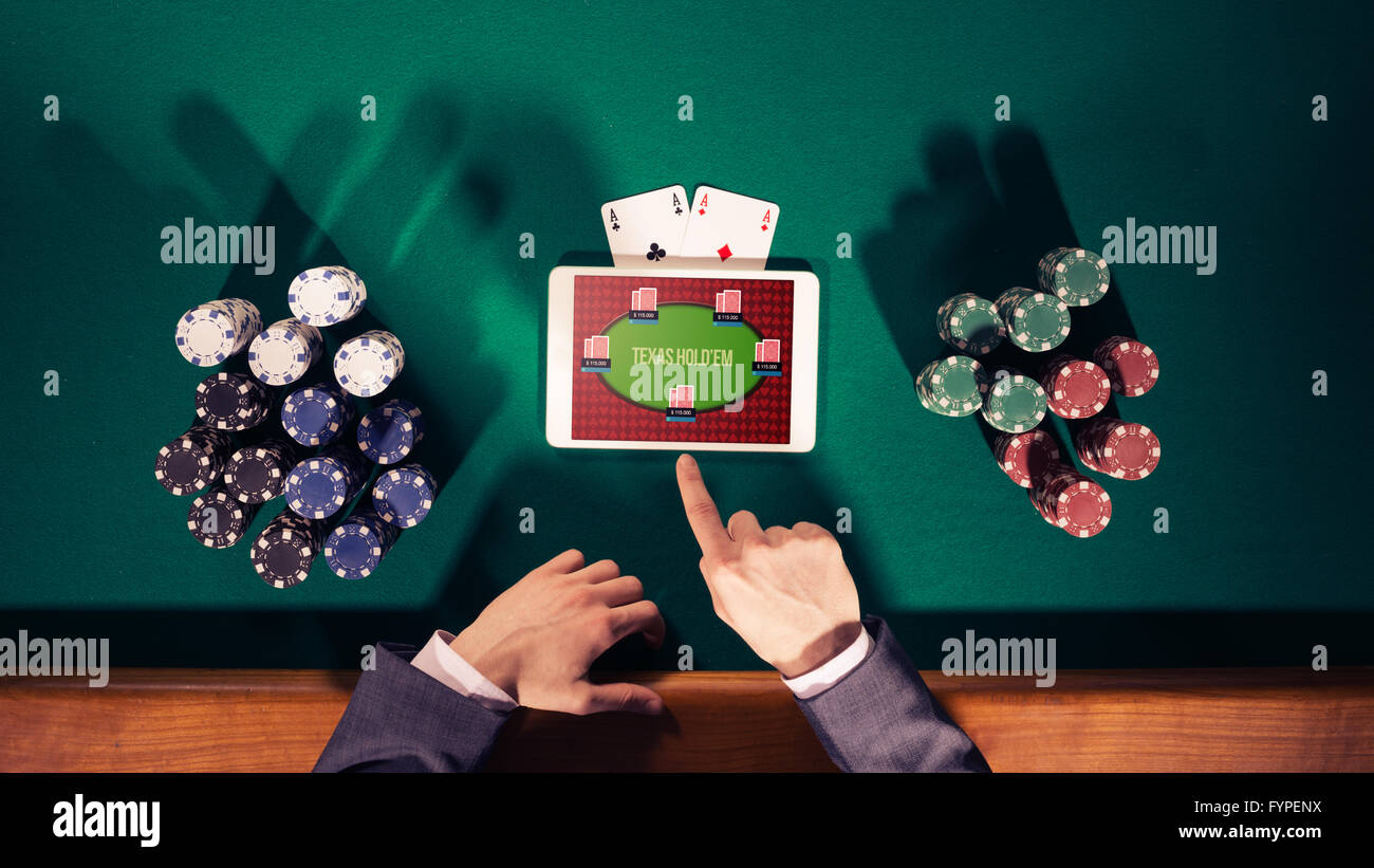 Poker player's hands with digital tablet, piles de jetons et cartes sur table verte, vue du dessus Banque D'Images