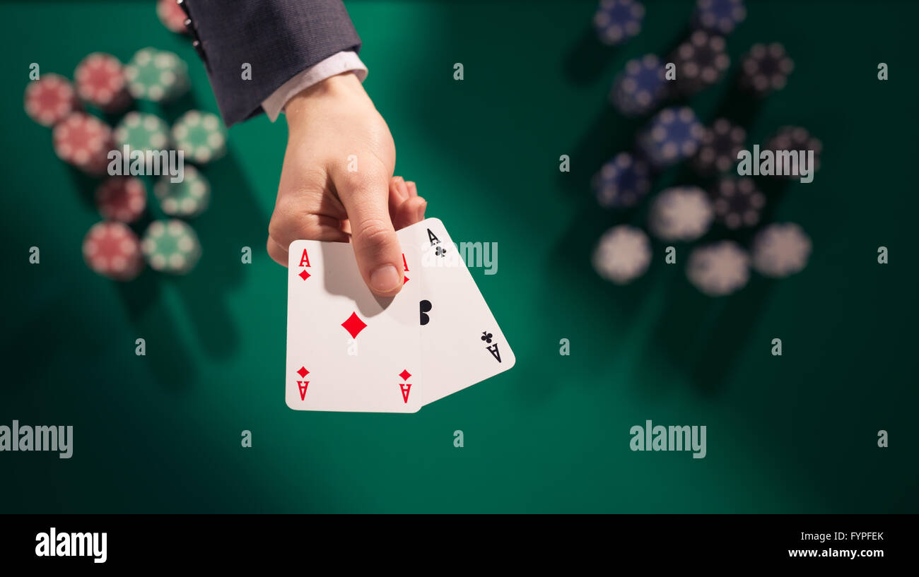 Joueur de poker homme élégant tenant deux As avec des piles de jetons sur la table verte et l'arrière-plan, Vue de dessus Banque D'Images