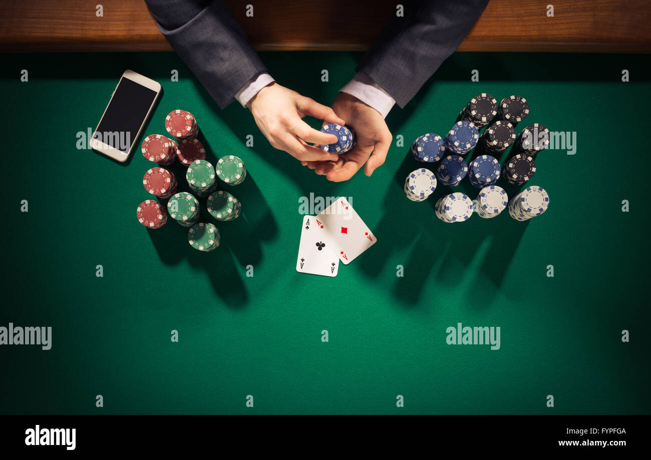 Joueur de poker homme élégant smartphone avec holding jetons, il a deux cartes de ace, les mains close up Vue de dessus Banque D'Images