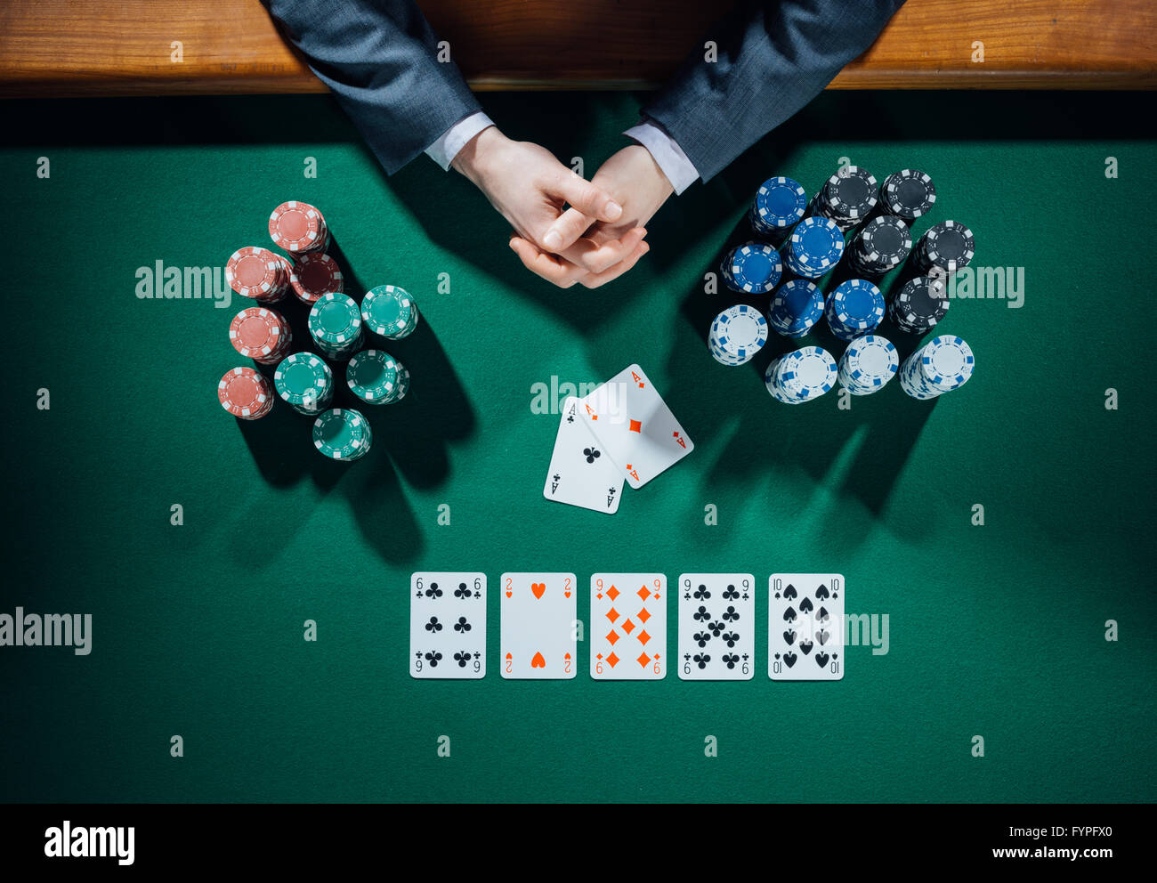 Les mains du joueur de poker avec des cartes et des piles de jetons tout autour sur le tableau vert, vue du dessus Banque D'Images