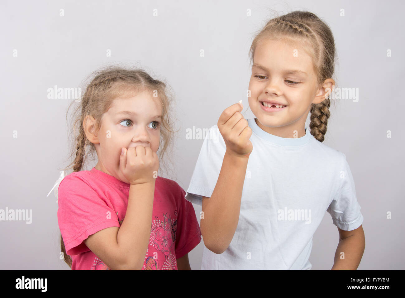 Fille de quatre ans, avec la crainte de voir la dent perdue dans sa main une petite fille de six ans Banque D'Images