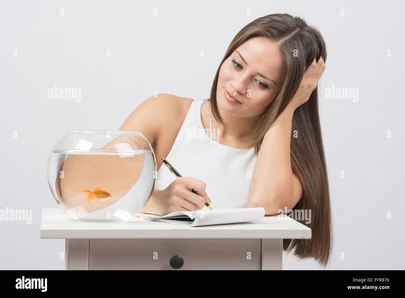 Girl écrit dans un carnet désir de remplir un poisson rouge Banque D'Images