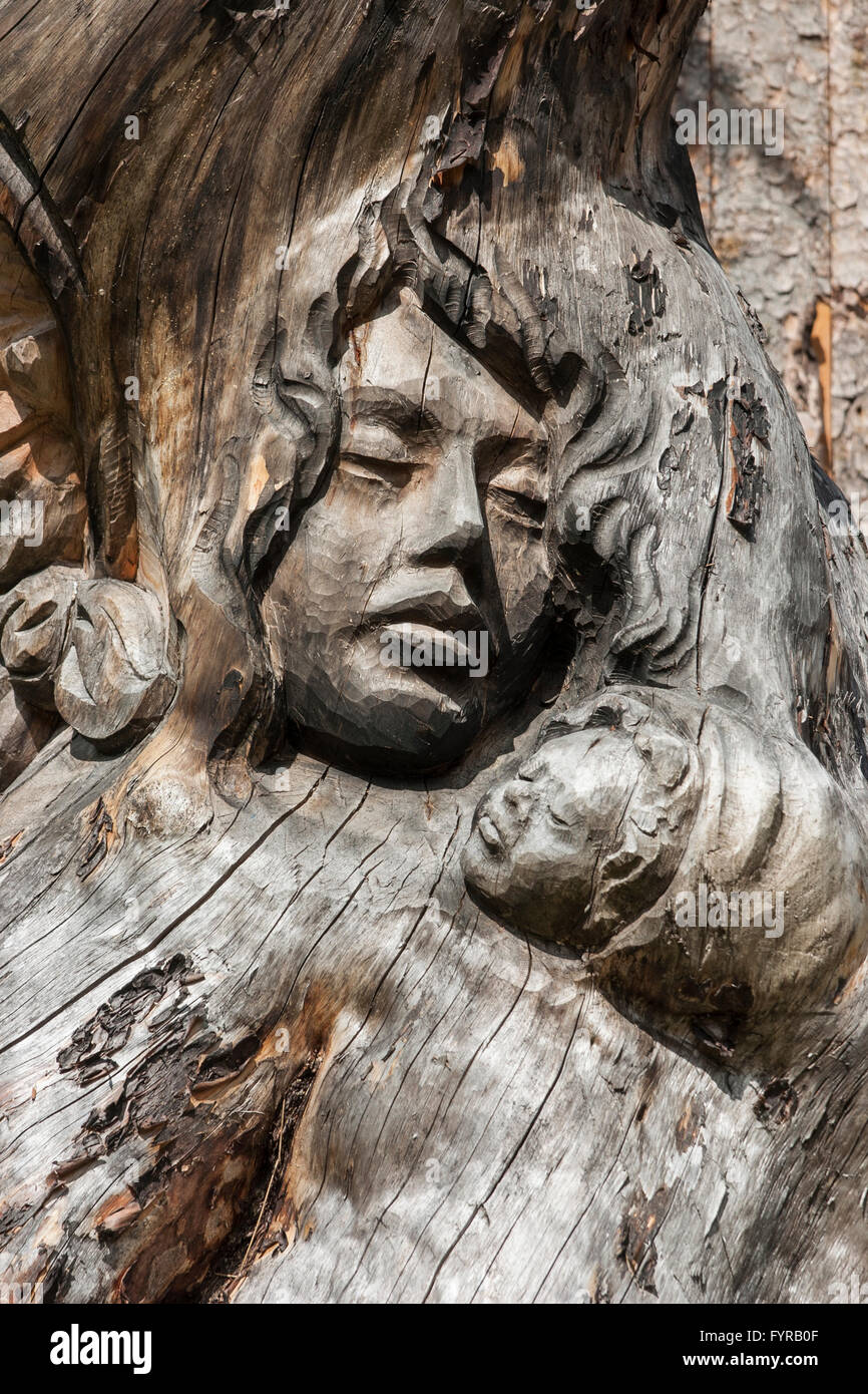 Visages sculptés dans du bois ; le long d'un chemin près de Canazei Trentin-Haut-Adige en Italie. Banque D'Images