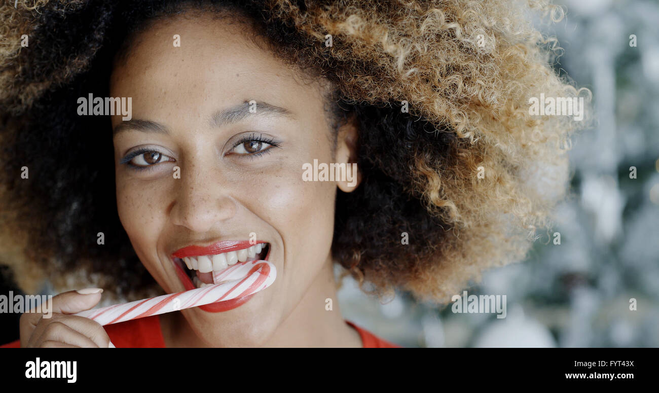 Young woman biting une canne de sucrerie de fête Banque D'Images