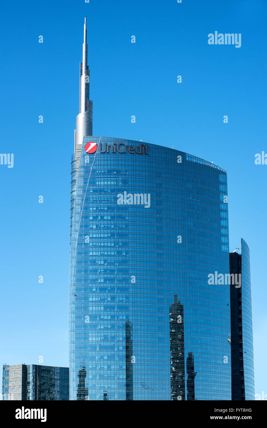 Haut de la moitié d'UniCredit bâtiment avec signalisation et autres bâtiments reflètent dans windows en face de ciel bleu clair à Milan, Italie Banque D'Images
