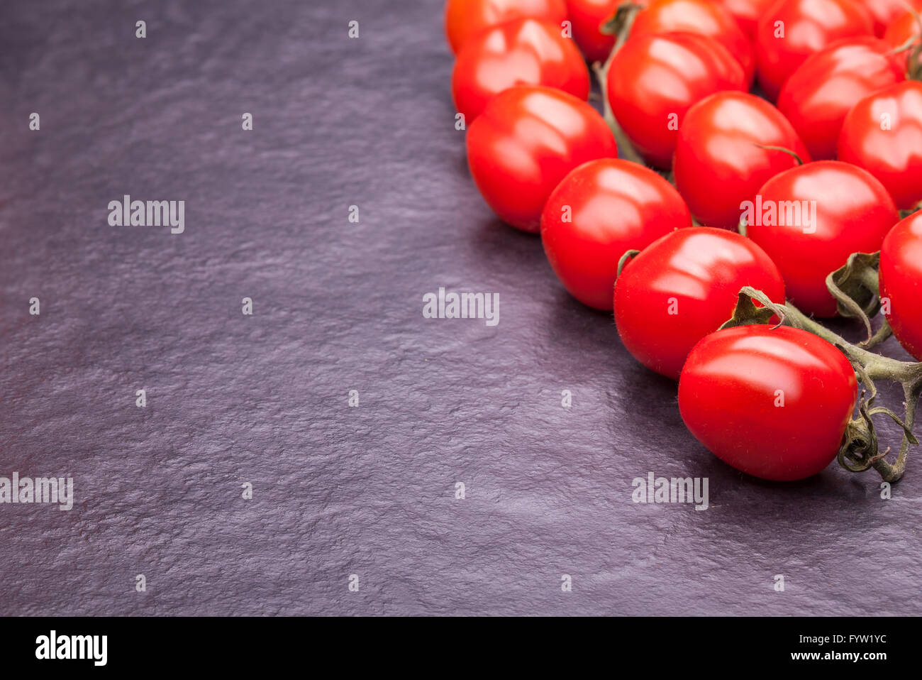 Les tomates sur une plaque en pierre noire Banque D'Images