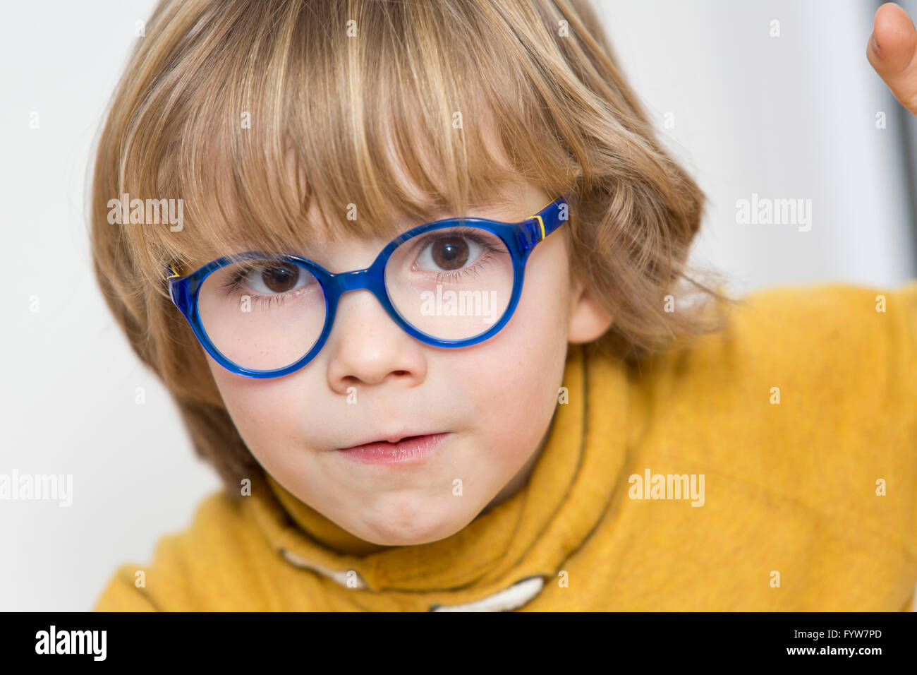 Jeune garçon, 6 ans, a l'air sympa, les sourires, avec des lunettes, avec un cadre bleu, Banque D'Images