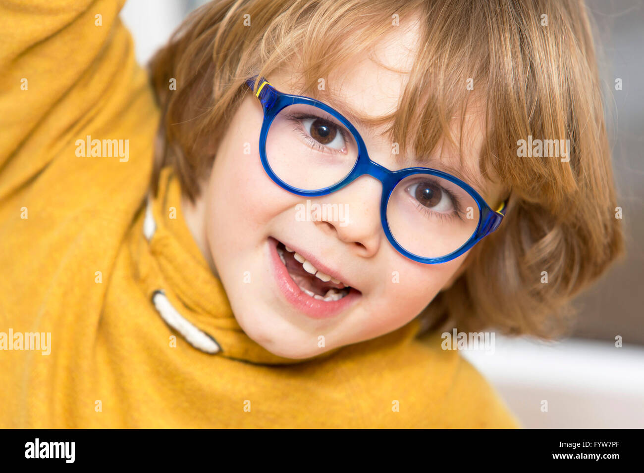 Jeune garçon, 6 ans, a l'air sympa, les sourires, avec des lunettes, avec un cadre bleu, Banque D'Images