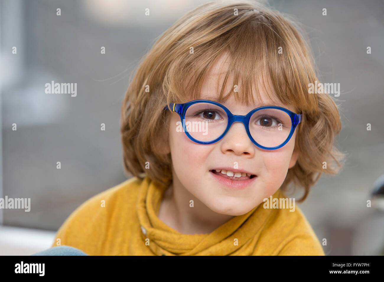 Jeune garçon, 6 ans, a l'air sympa, les sourires, avec des lunettes, avec un cadre bleu, Banque D'Images