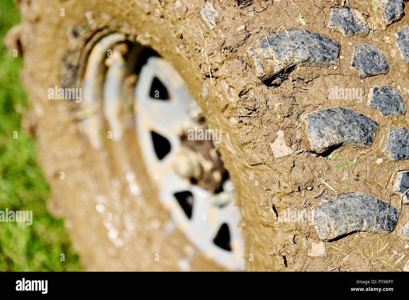 Gros véhicule off road pneu et roue pleine de boue sur l'herbe verte Banque D'Images