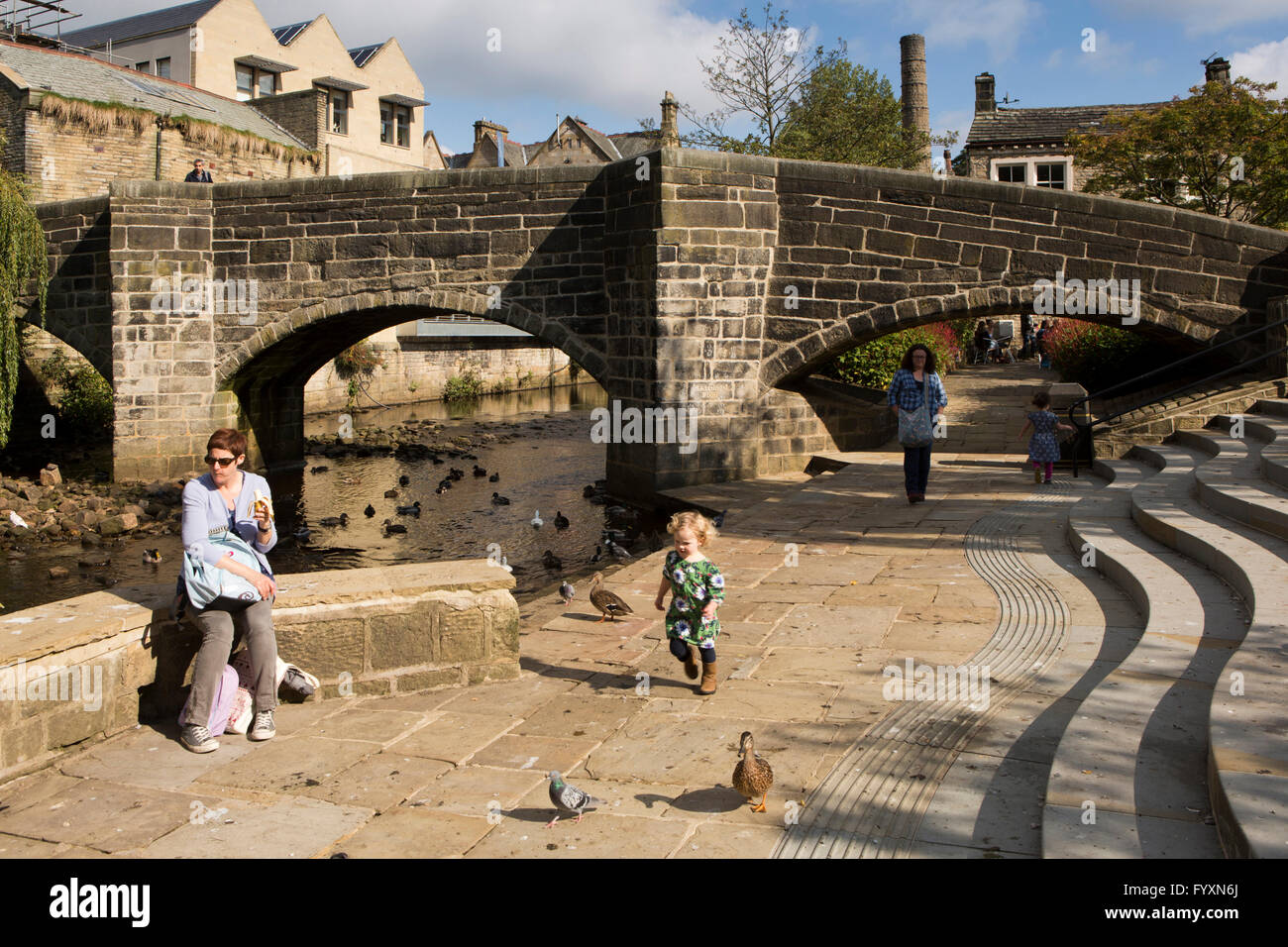 Royaume-uni, Angleterre, dans le Yorkshire, Calderdale Hebden Bridge, jeune enfant chasing ducks ci-dessous vieux pont à cheval Banque D'Images