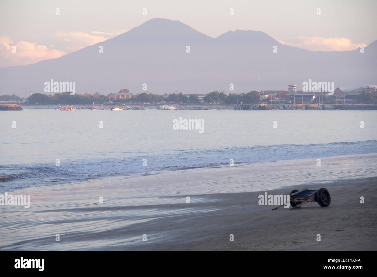 Une remorque en bois pour le lancement de bateaux dans la baie de Jimbaran, Bali, tôt le matin, et les montagnes au loin. Banque D'Images