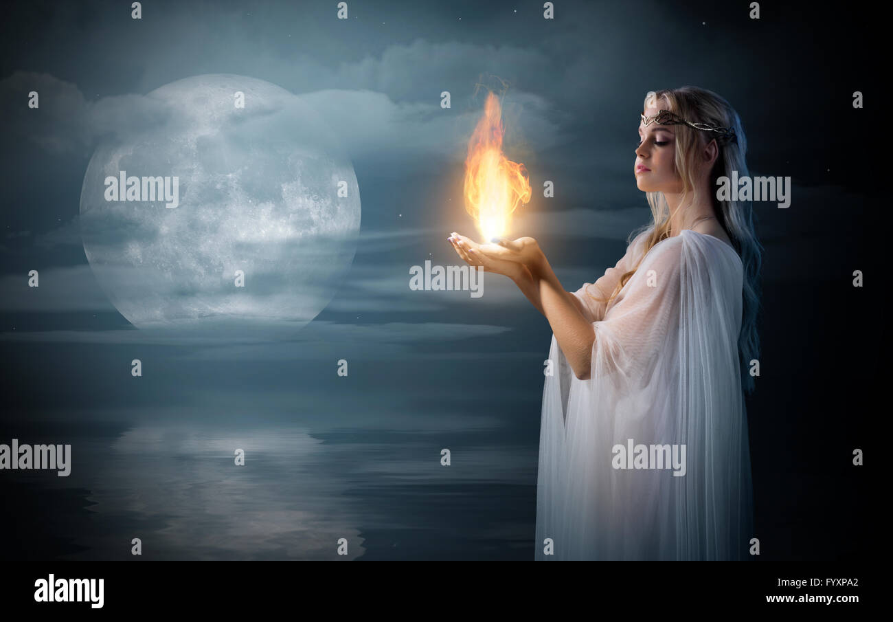 Young Girl holding elven fire en palms at sea shore Banque D'Images