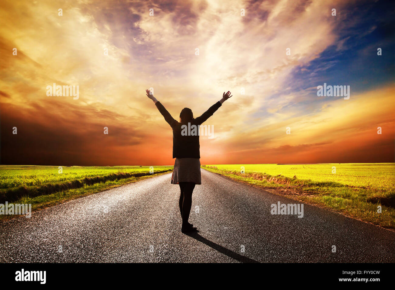 Happy woman standing on longue route au coucher du soleil Banque D'Images