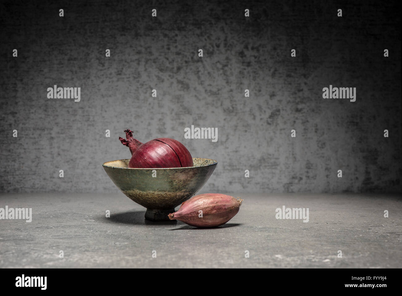 La vie toujours des aliments avec l'oignon rouge dans un bol et l'échalote sur table en pierre dans une cuisine moderne. Banque D'Images
