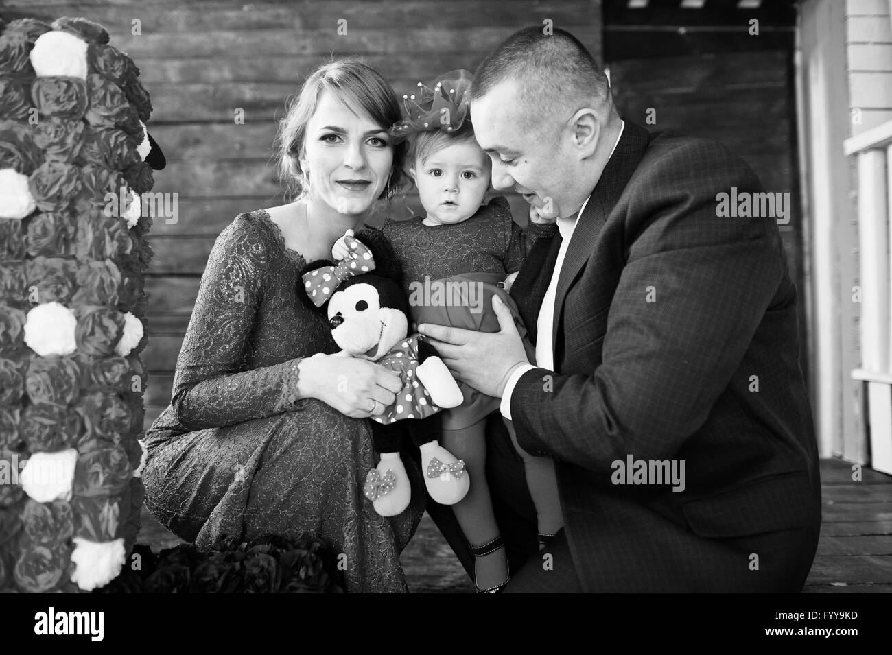 Famille heureuse et sa fille avec 1 an d'anniversaire faites à la main à l'ancien numéro de décor maison en bois. Photo en noir et blanc Banque D'Images