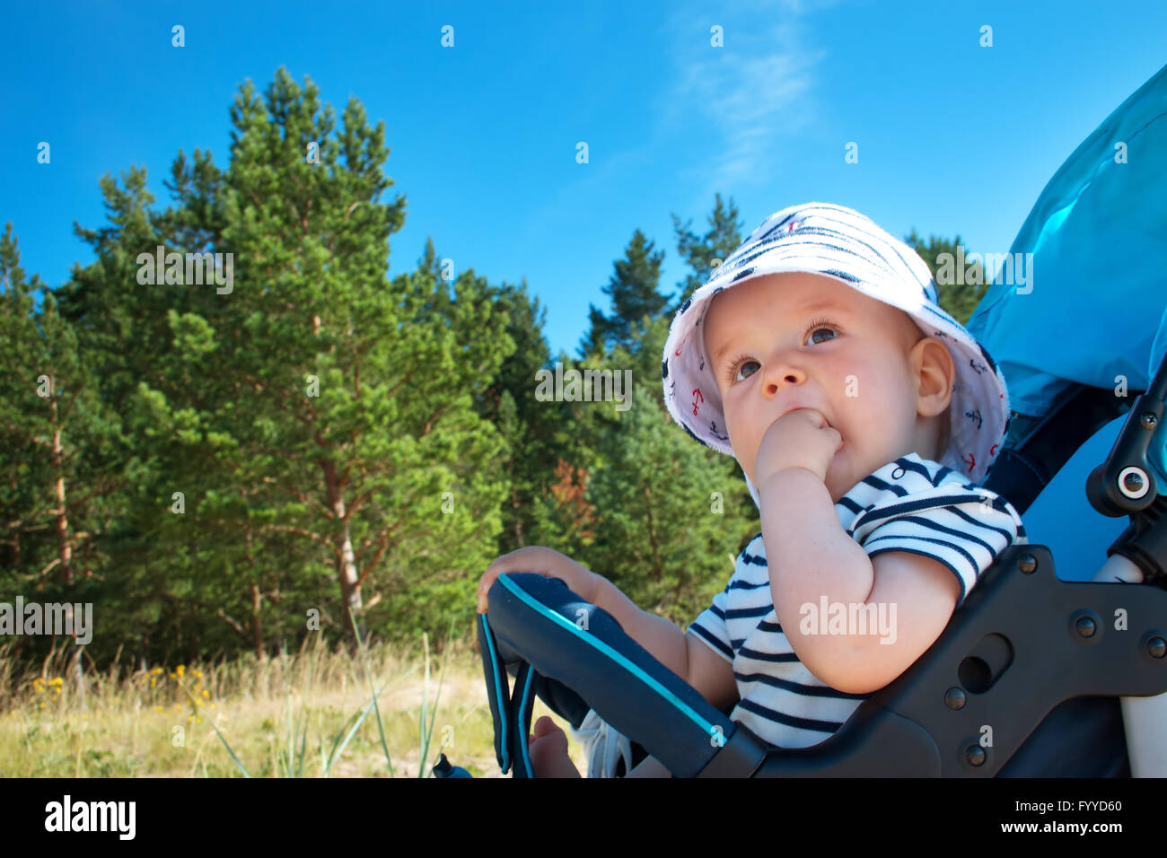 Petit bébé garçon assis dans la poussette à jour d'été Banque D'Images