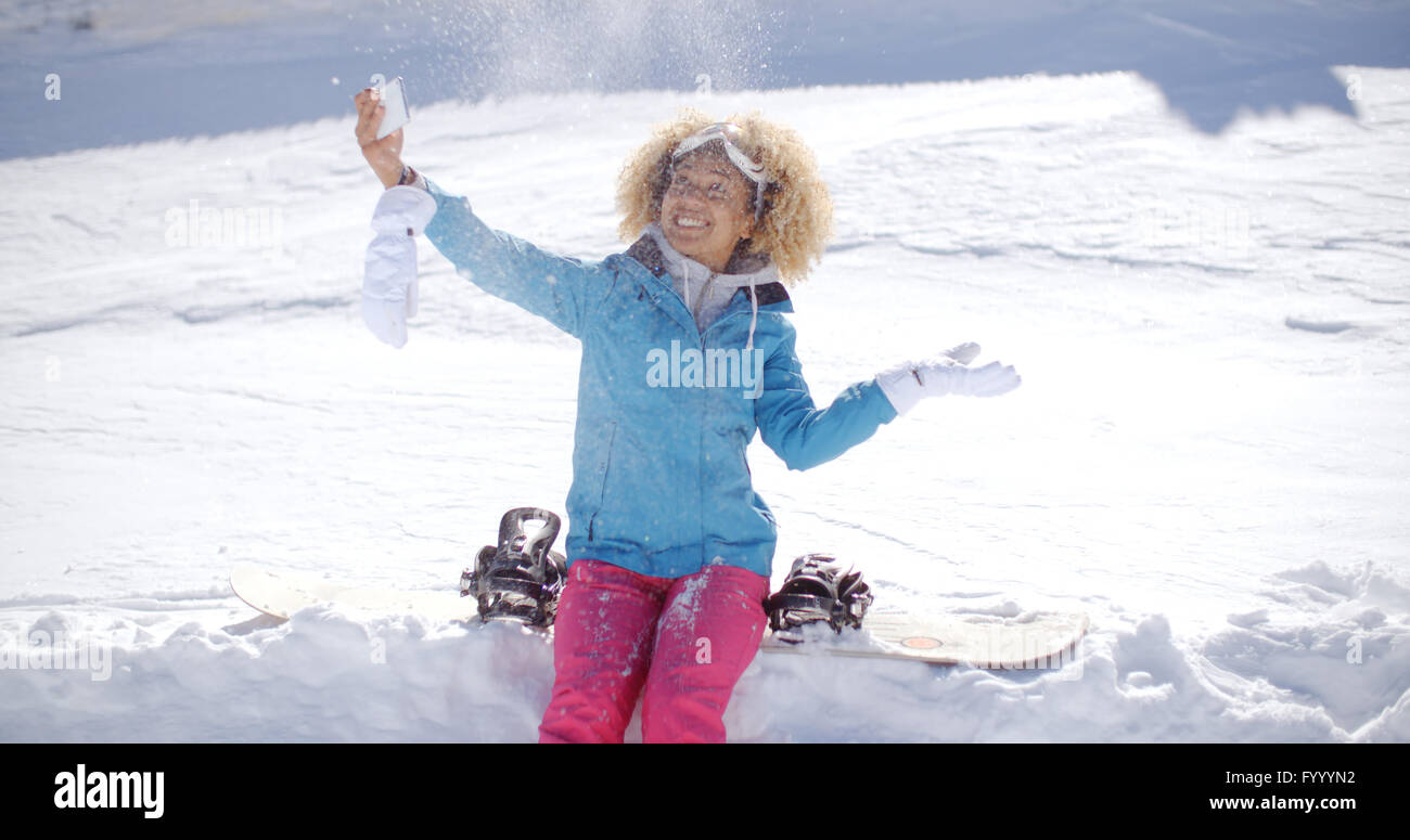 Posant pour une femme espiègle dans la neige selfies Banque D'Images